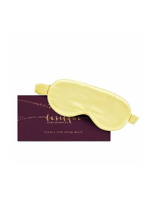 Maschera da sonno in seta gialla poggiata su una scatola rettangolare viola scura con testo dorato che recita "lesilque pure moments luxury silk sleep mask."