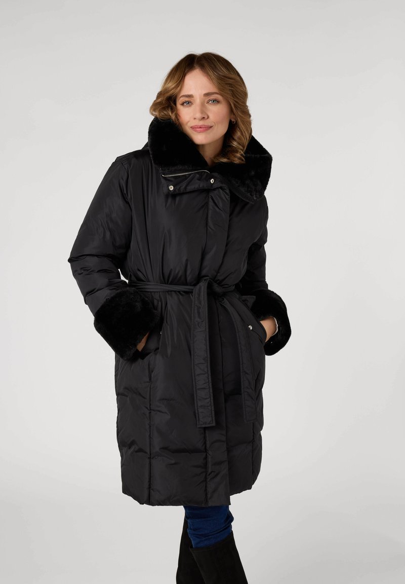 Zwarte gewatteerde jas met een brede faux fur kraag en manchet, met een ceintuur in de taille. Voorzien van ritssluitingen en drukknoopsluitingen, en zijzakken.