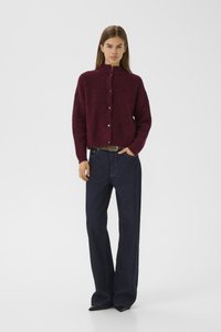 Burgunderfarget kort cardigan laget av teksturert materiale med høy krage og frontknapper, kombinert med høyt liv blå vide bukser.
