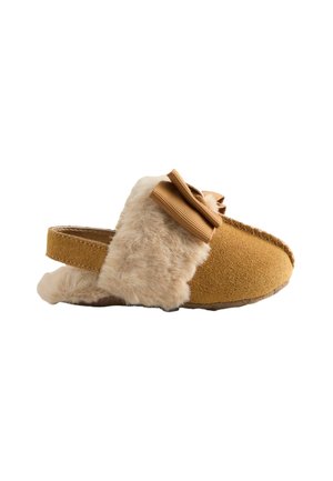 Faux bont en mosterdsuède instapslipper met een grote decoratieve strik, open achterkant, zachte textuur en contrasterende tan afwerking.