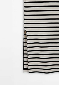 Tissu rayé horizontal noir et blanc avec une fente latérale sur un vêtement, sur un fond blanc uni.