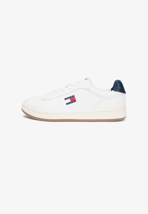Witte sneaker met lage schacht, beige zool, marineblauwe hieltab en klein Tommy Jeans-logo aan de zijkant.