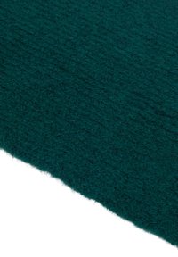 Teal tekstureret stof med en fuzzy overflade, der har en ru kant. Materialet virker tykt og varmt, hvilket minder om uld eller et lignende tekstil.