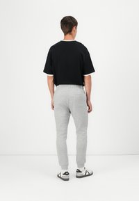 Black short-sleeve t-shirt with white cuff accents, paired with light gray sweatpants featuring an elastic waistband and tapered legs.