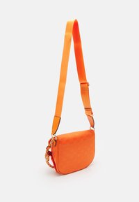 Oranžová crossbody taška se hladkým povrchem, vzorem loga, nastavitelným popruhem a řetízkovým akcentem na jedné straně.