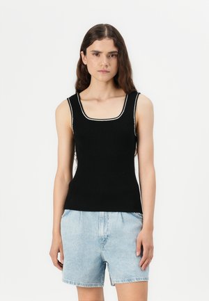 Canotta nera a costine con scollatura quadrata e rifiniture bianche a contrasto. Abbinata a shorts in denim azzurro chiaro.
