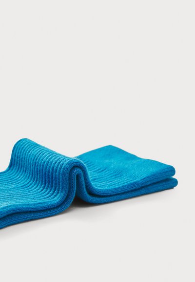 Blå strikkede strømper med ribbet tekstur, der har en glat, ensartet farve og en foldet design, som fremviser stoffets fleksibilitet og blødhed.