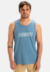 Lyseblå bomulds tanktop med rund hals, der har et kontrasterende Quiksilver-logo i hvid, grøn og pink på forsiden.