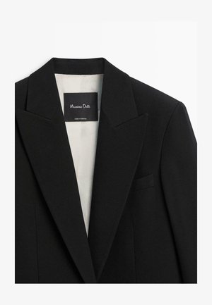 Svart blazer med strukturerad design, spetsiga slag, en bröstficka och ljus foder. Etiketten lyder "Massimo Dutti, Made in Portugal."