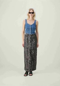 Top scurt din denim cu închidere prin butoane, asortat cu o fustă lungă cu imprimeu leopard. Pantofi cu toc deschis, negri, și ochelari de soare mici, negri, completează ținuta.