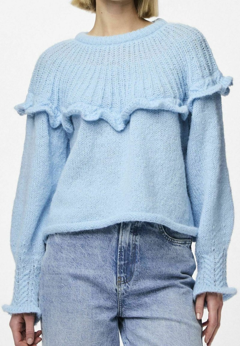 Pull en tricot bleu clair avec un design froncé le long de l'encolure et des poignets. Présente des manches longues et une coupe décontractée.