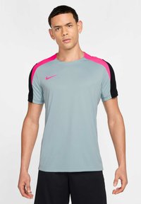 Maglietta sportiva grigia con accenti rosa e neri. Maniche corte, scollatura rotonda e un tessuto texture. Logo Nike sul petto.