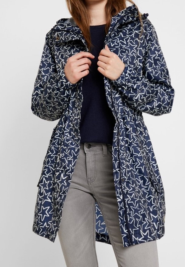 Navy blue rain jacket with white star pattern, adjustable hood, elastic waist, and front zip closure. Lightweight material, mid-length design.