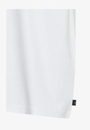 White cotton t-shirt with a smooth texture, relaxed fit, and a small black fabric tag on the lower side seam. No visible patterns.