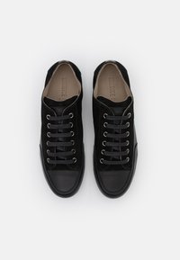 Sorte semskede sneakers med en glat sort læder tåkap, runde snørebånd trukket gennem metaløjer, og en beige indersål.