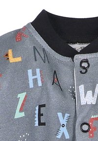 Graue Stoffjacke mit schwarzem Kragen, die bunte Buchstaben und Symbole in verschiedenen Schriftarten und Größen zeigt. Auffälliges Knopfdetail auf der Vorderseite.