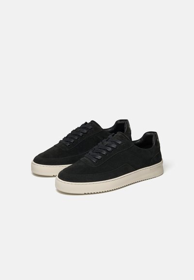 Par sorte lave sneakers med hvide gummisåler og sorte snørebånd placeret på en lysegrå baggrund.