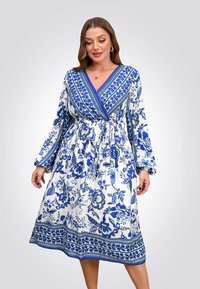 Blauwe en witte bloemenjurk met lange mouwen, diepe V-hals, gegatherde taille en gedessineerde accenten langs de zoom en de mouwen.