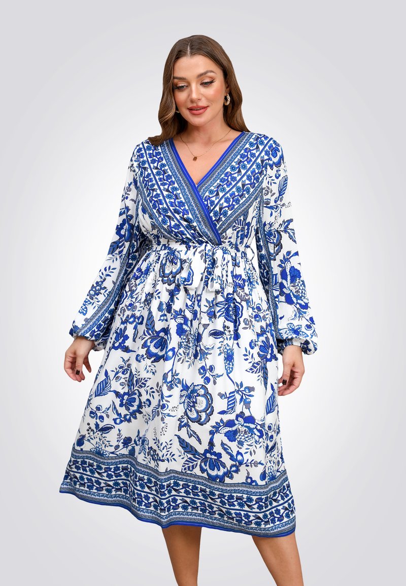 Blauwe en witte bloemenjurk met lange mouwen, diepe V-hals, gegatherde taille en gedessineerde accenten langs de zoom en de mouwen.