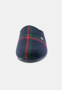 Pantofola di lana blu navy con un motivo tartan rosso e verde, forma arrotondata, texture morbida e suola in gomma nera. Dettaglio del logo in metallo laterale.