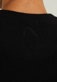 Maglione nero in maglia con una texture a coste. Presenta un piccolo filo visibile vicino al collo, che indica un dettaglio nel tessuto.
