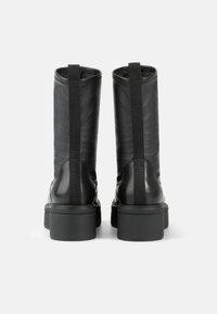 Botas de tobillo de cuero negro con un acabado suave, que cuentan con una trabilla, paneles laterales elásticos y una suela de goma gruesa.