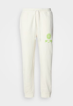 Kremfargede joggebukser laget av bomullsblanding, med elastisk midjebånd, snor og en lys grønn trykket smiley-logo på forsiden.