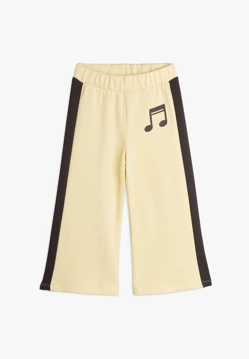 Svetlo rumene hlače iz džersija s širokimi nogavicami, z črnimi stranskimi črtami in grafiko notnega zapisa na levi strani. Elastični pas.