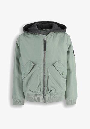 Jasnozielona pikowana kurtka z przednim zamkiem błyskawicznym, dwoma kieszeniami z patkami na guziki, ściągaczami na rękawach i na dole oraz ciemnoszarym podszyciem kaptura.