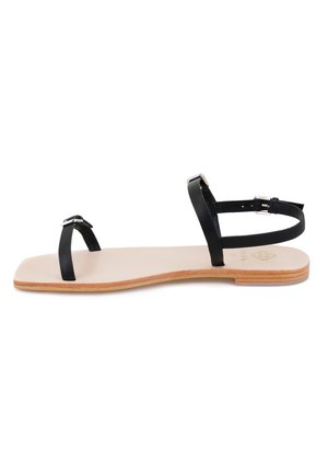 Zwarte leren platte sandalen met dunne bandjes, een minimalistisch ontwerp en een lichtbeige zool met subtiele textuur en een houten accent.