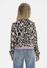 Kurtka bomberka w panterkę wykonana z gładkiej tkaniny, z prążkowanym różowo-białym obszyciem u dołu, z długimi rękawami i luźnym krojem.