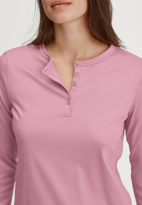 Langsleeve roze henleytop van zachte stof, met een knoopsluiting en een ronde halslijn. Gladde textuur met een fitted ontwerp.