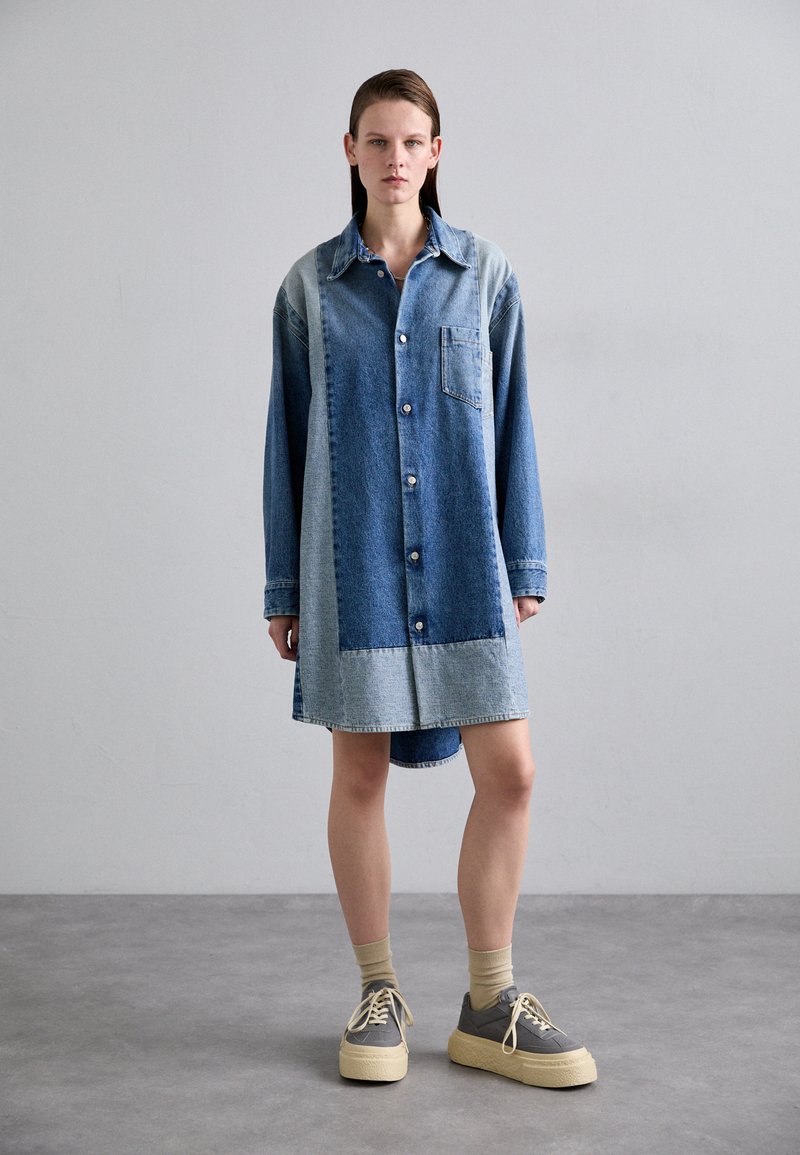 Džinsa krekla kleita, kurai ir gaismas un tumšā mazgāšanas maisījums, pogu aizdare, apkakles piespraude un krūšu kabata. Mīksta tekstūra, garas piedurknes un asimetrisks apakšmalas dizains.