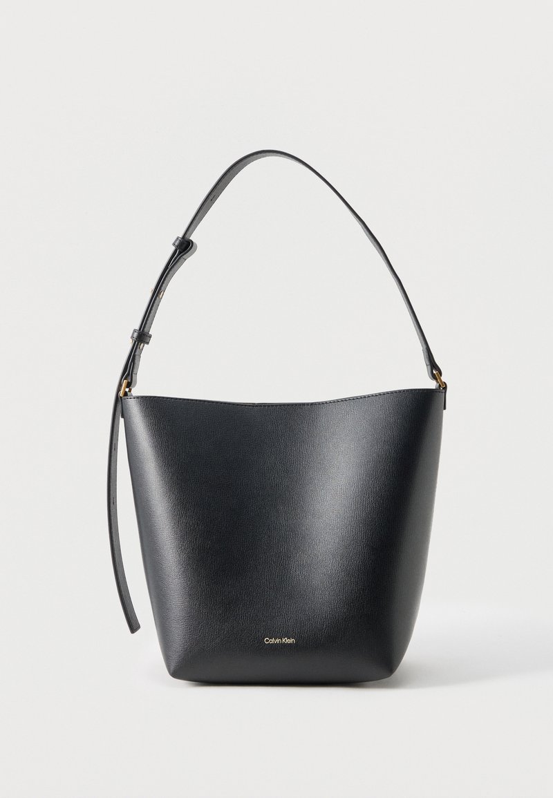 Μαύρη δερμάτινη τσάντα τύπου κάδος με ρυθμιζόμενο λουράκι ώμου και μικρό χρυσό λογότυπο Calvin Klein στο μπροστινό μέρος.