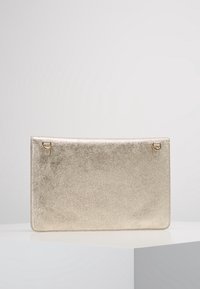 Gold metallic clutch bag with a smooth texture, rectangular shape, and two small hardware rings on the top corners. Simple and sleek design.