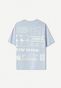 Light blue t-shirt made of soft fabric, featuring white graphic designs and text on the back, including logos and patterns.