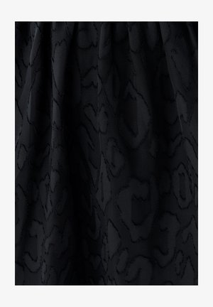 Zwarte stof met subtiele verhoogde luipaardprinttextuur en zachte plooien.