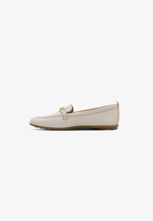 Beige leren platte loafer met gouden kettingdetail, afgeronde neus en bruine rubberen zool, gezien vanaf de binnenkant op een witte achtergrond.