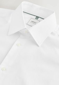 Weißes Hemd aus strukturiertem Stoff, mit Button-Down-Kragen, zwei vorderen Knöpfen und einem "NEXT Tailoring"-Label im Kragen.