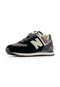 Sneaker nere e grigie in materiali scamosciati e in rete, con una spessa suola intermedia bianca, punta arrotondata e un prominente logo 'N' sul lato.
