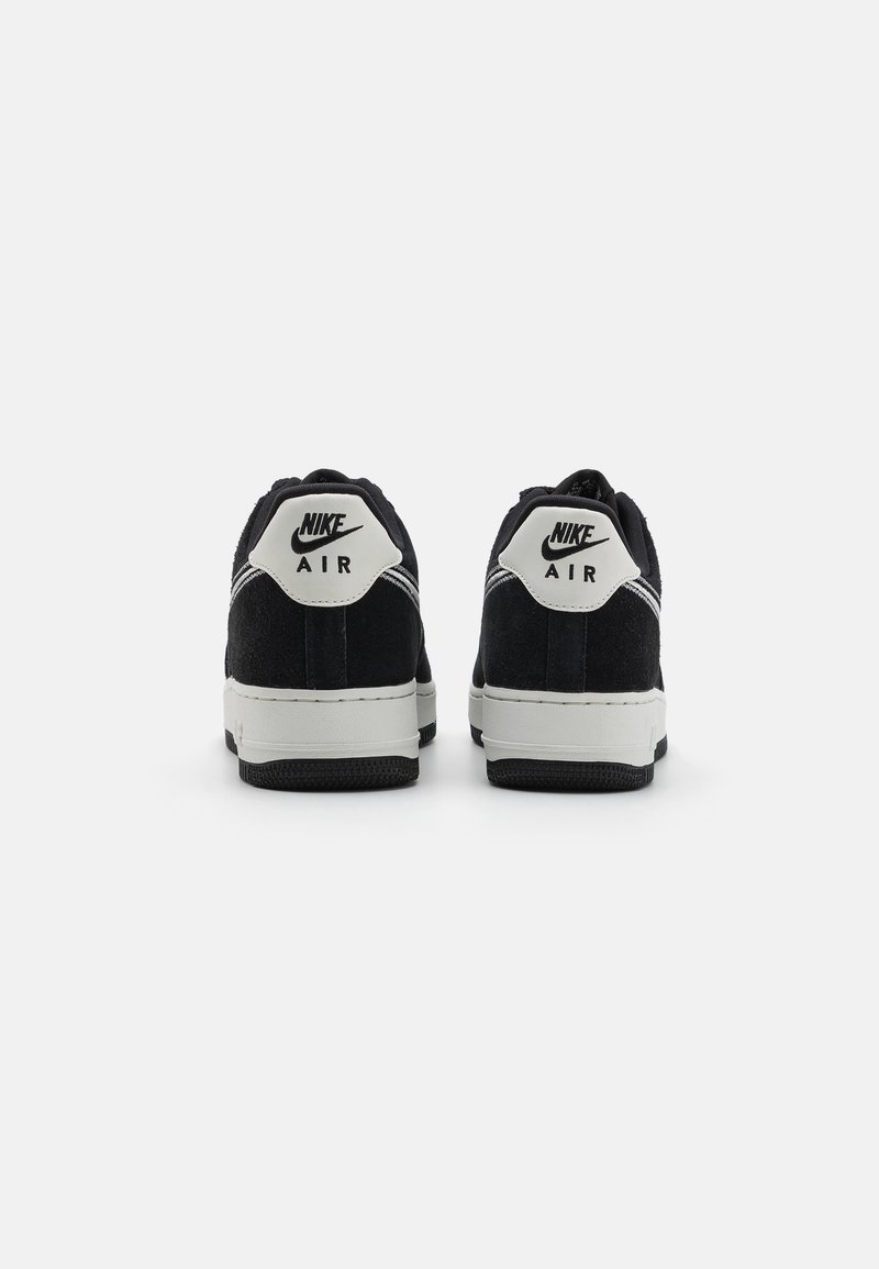 Zwarte suède Nike Air sneakers met witte accenten, voorzien van een gewatteerde kraag, iconisch logo op de hak en een gestructureerde rubberen zool.