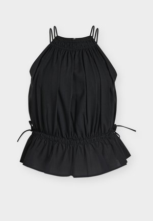 Kobieta w czarnym, bezrękawnym topie na szyję z falbanką w talii, długiej czarnej spódnicy, czarnych sandałach na obcasie i trzymająca czarną kopertówkę.