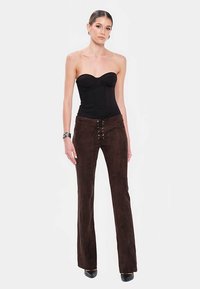 Brązowe rozkloszowane spodnie zamszowe z sznurowaniem z przodu, zestawione z czarnym, bezrękawnym topem. Gładka faktura, dopasowany krój i długa długość.