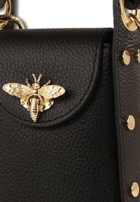 Black leather handbag featuring a gold bee embellishment on the flap, with gold studs on the strap. Textured surface adds depth.