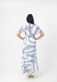 Robe maxi avec un motif tourbillonnant bleu et blanc, en tissu semi-transparent, manches courtes volantées et taille cintrée avec une fermeture à nouer.