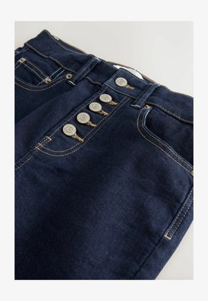 Mørkeblå denim bukser med høj talje, fem lommer og knaplukning. Har kontrasterende tan syninger og metal knapdetaljer.