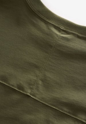 Pametna majica od pamuka maslinasto zelene boje s okruglim izrezom, glatke teksture i vidljivim šavovima duž kroja ramena.