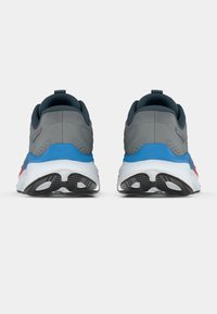 Paire de chaussures de sport grises avec semelles bleues et blanches, vues de dos sur un fond blanc.