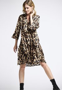 Leopardenmuster-Kleid in Beige und Schwarz, aus glattem Stoff, mit einem mehrstufigen Design, dreiviertelärmeln und einem V-Ausschnitt.