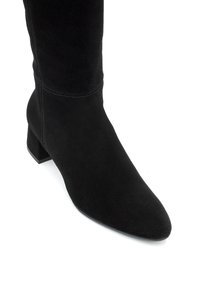 Crne nubuk čizme do koljena s šiljastim vrhom i niskim blok petom. Imaju glatku teksturu i suptilno šivanje oko gležnja.